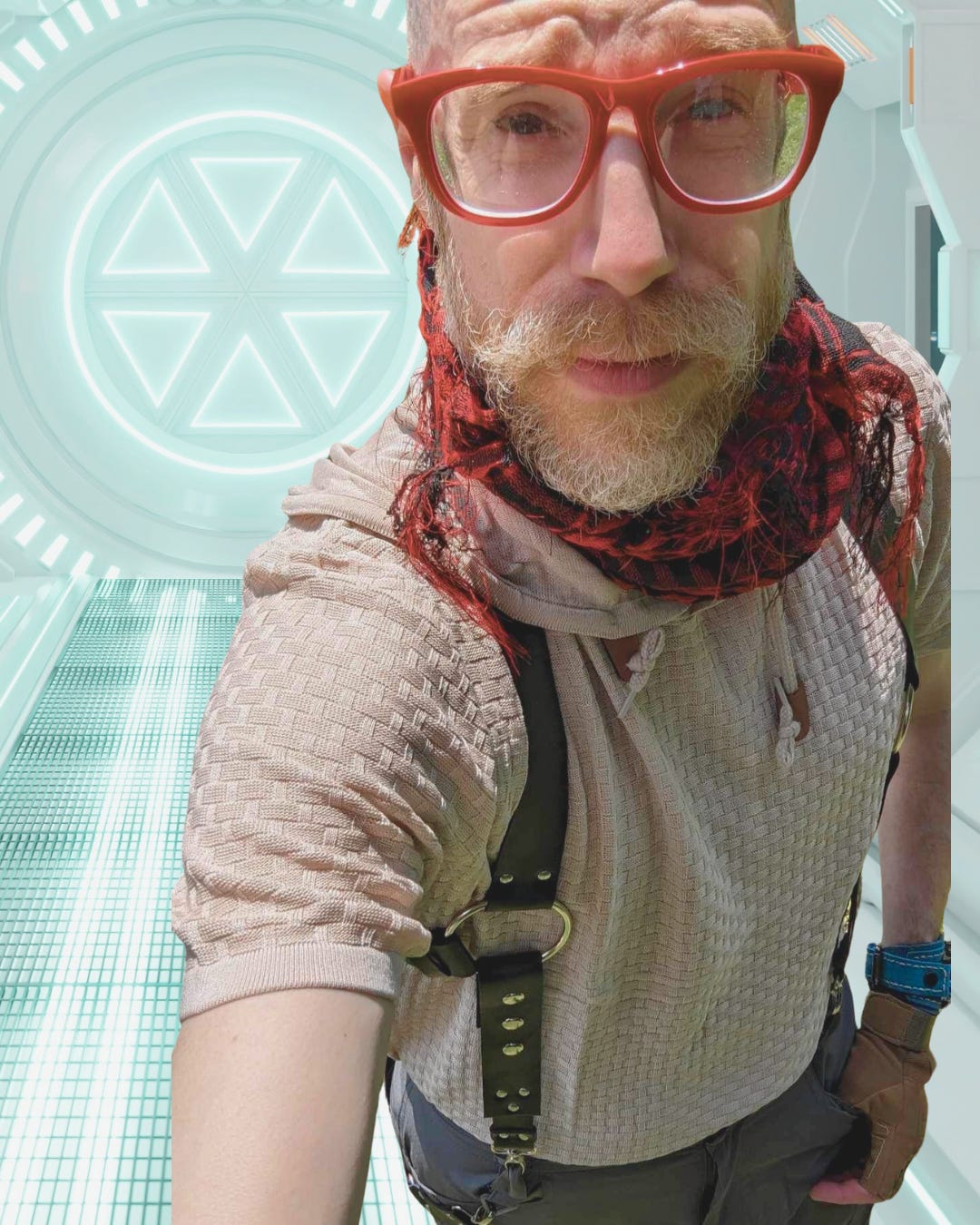 Pale-skinned man with bald head and gingery beard, wearing red glasses, an off-white shirt, a red scarf, and a leather holster, standing in what appears to be a starship hallway