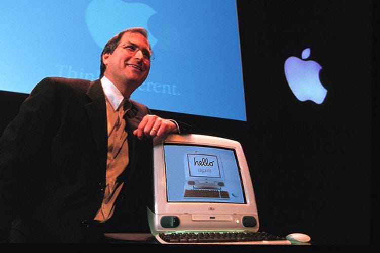 Steve Jobs standing next to the just-unveiled iMac G3.