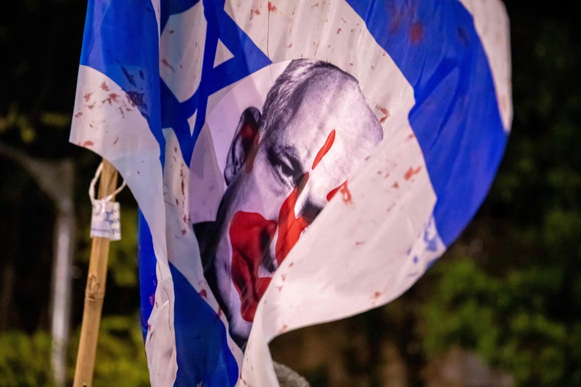 netanyahu's face on a bloody israeli flag during protest