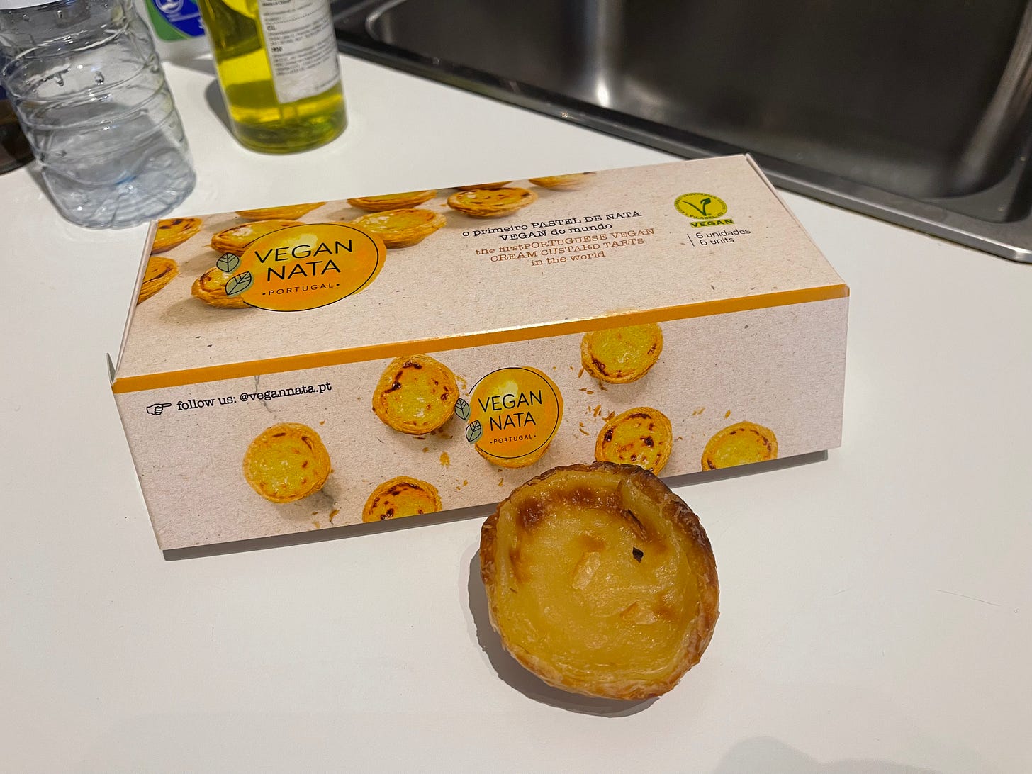 A box of vegan pastéis de nada on a table, one pastel in front of the box