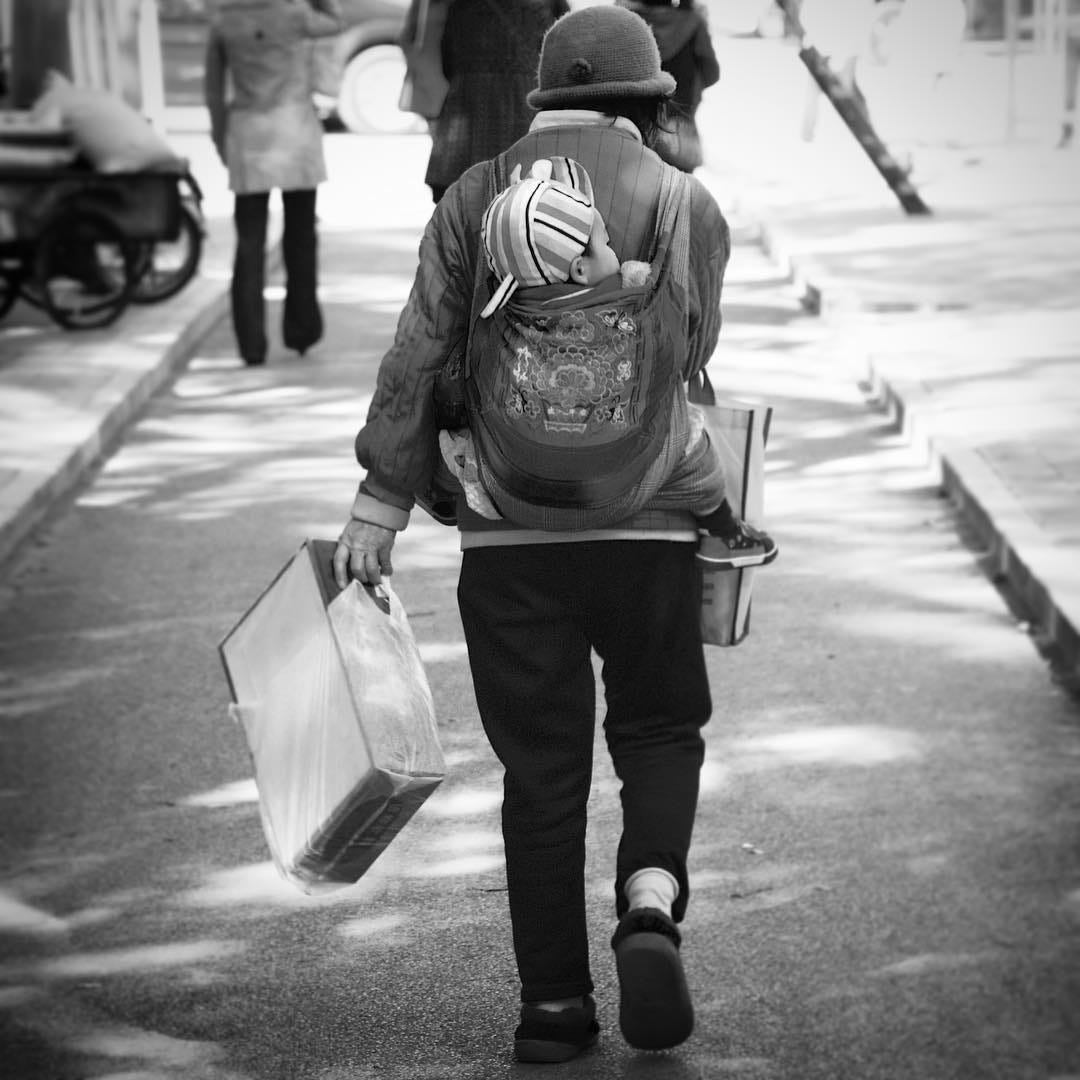 Grandmother carrying her grandchild on her back, Beijing.