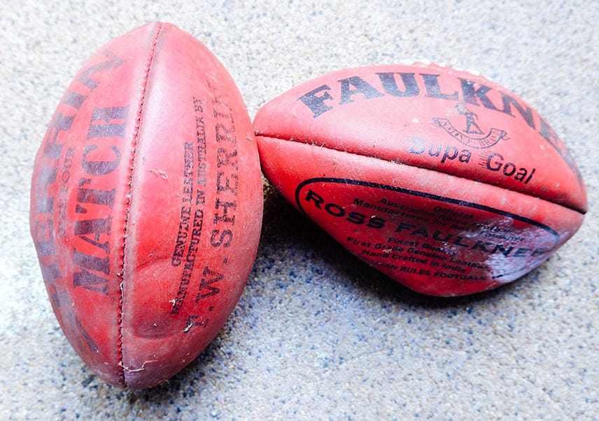 Two footballs that have seen better days.