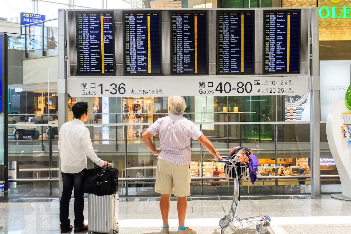 Free People Looking at Departure Board at an Airport Stock Photo