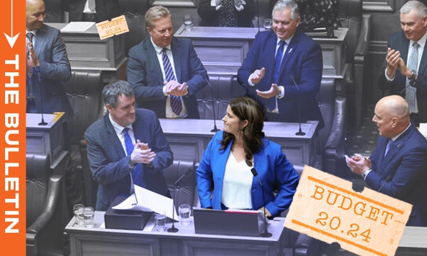 "Photograph of a parliamentary session with a focus on Nicola Willis in a blue blazer speaking at a podium. She is surrounded by applauding members of parliament. 'Budget 2024' graphics are overlaid in the corners of the image."