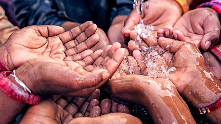 Water pouring into hands of African children