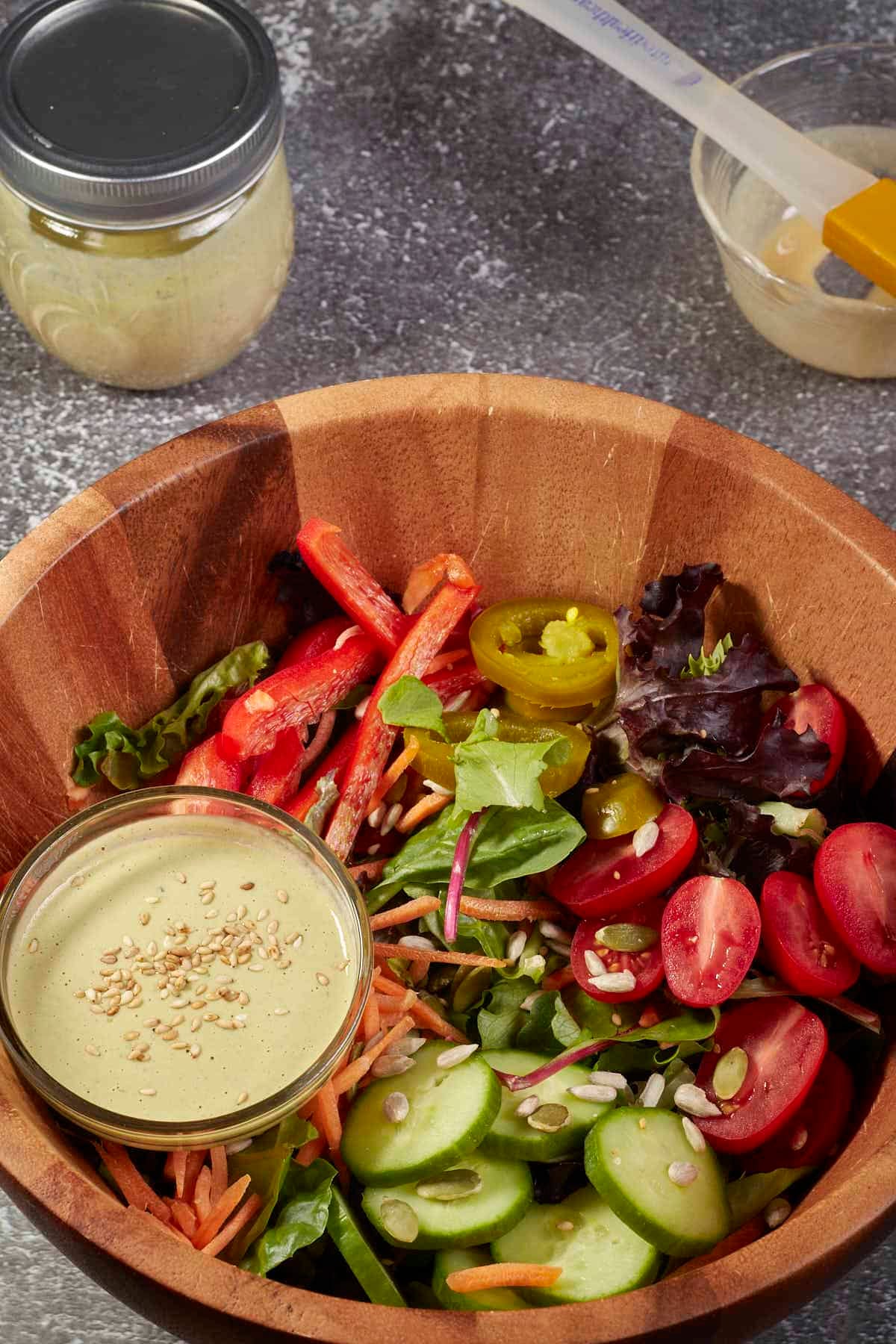 salad with a jar of vegan tahini salad dressing on the side