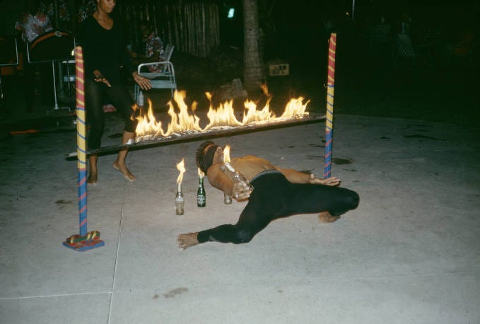 Trinidad and Tobago, man performing limbo dance under flaming bar 