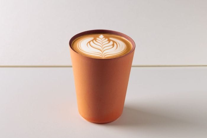 A plain clay tumbler with latte art