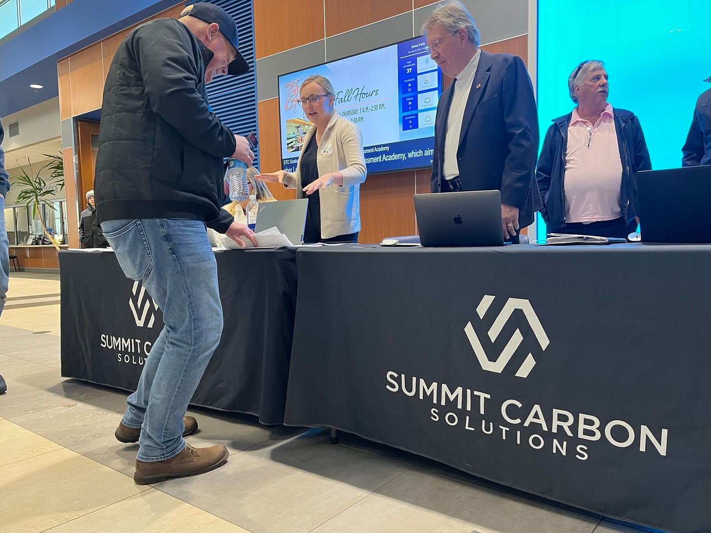 Representatives with Summit Carbon Solutions hand out information and answer questions ahead of the Public Utilities Commission public hearing in Sioux Falls on Jan. 15, 2025. (Makenzie Huber/South Dakota Searchlight)