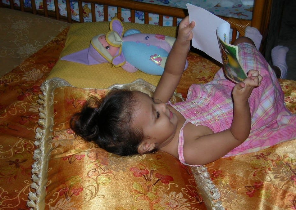 Toddler girl reading book to doll