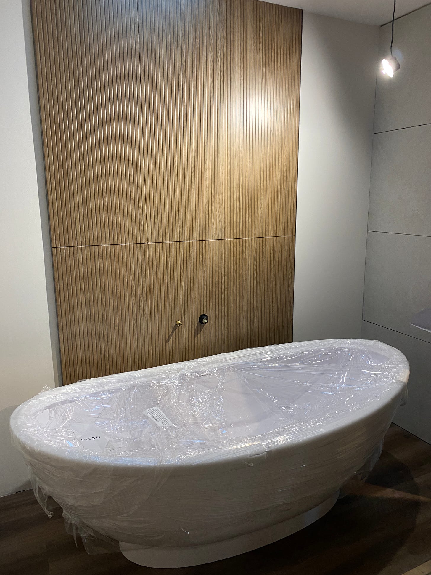 white bath positioned in front of brown wall tiles