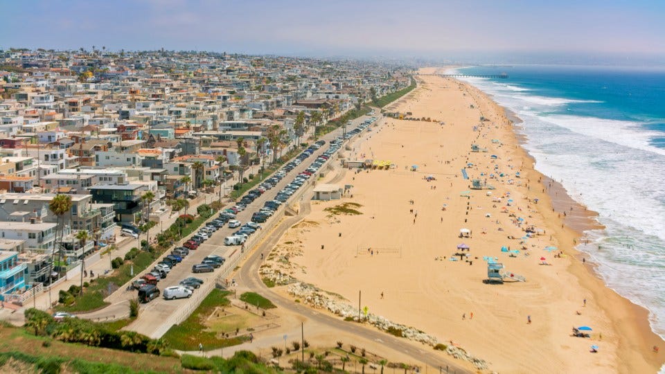 Aerial view of Huntington Beach, California, showing residential buildings, a beach with people, and the ocean. Aerial view of Huntington Beach, California, showing residential buildings, a beach with people, and the ocean.