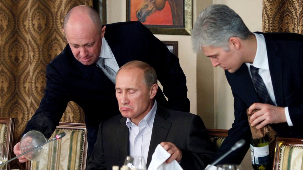 Yevgeny Prigozhin (left) pictured serving Vladimir Putin (centre) at a dinner in 2011. 