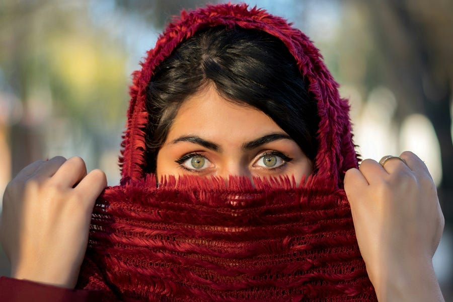 Woman wearing a red scarf covering half her face Woman wearing a red scarf covering half her face