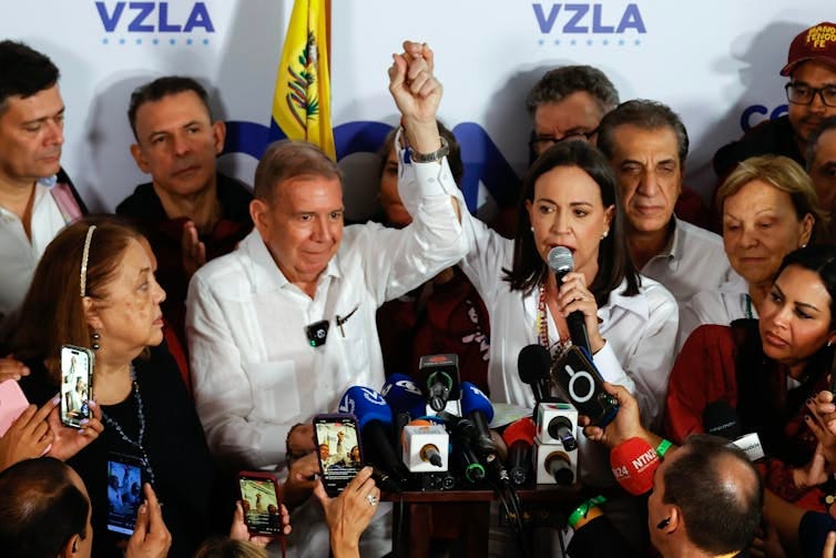 Machado holding González's hand aloft at a press conference.