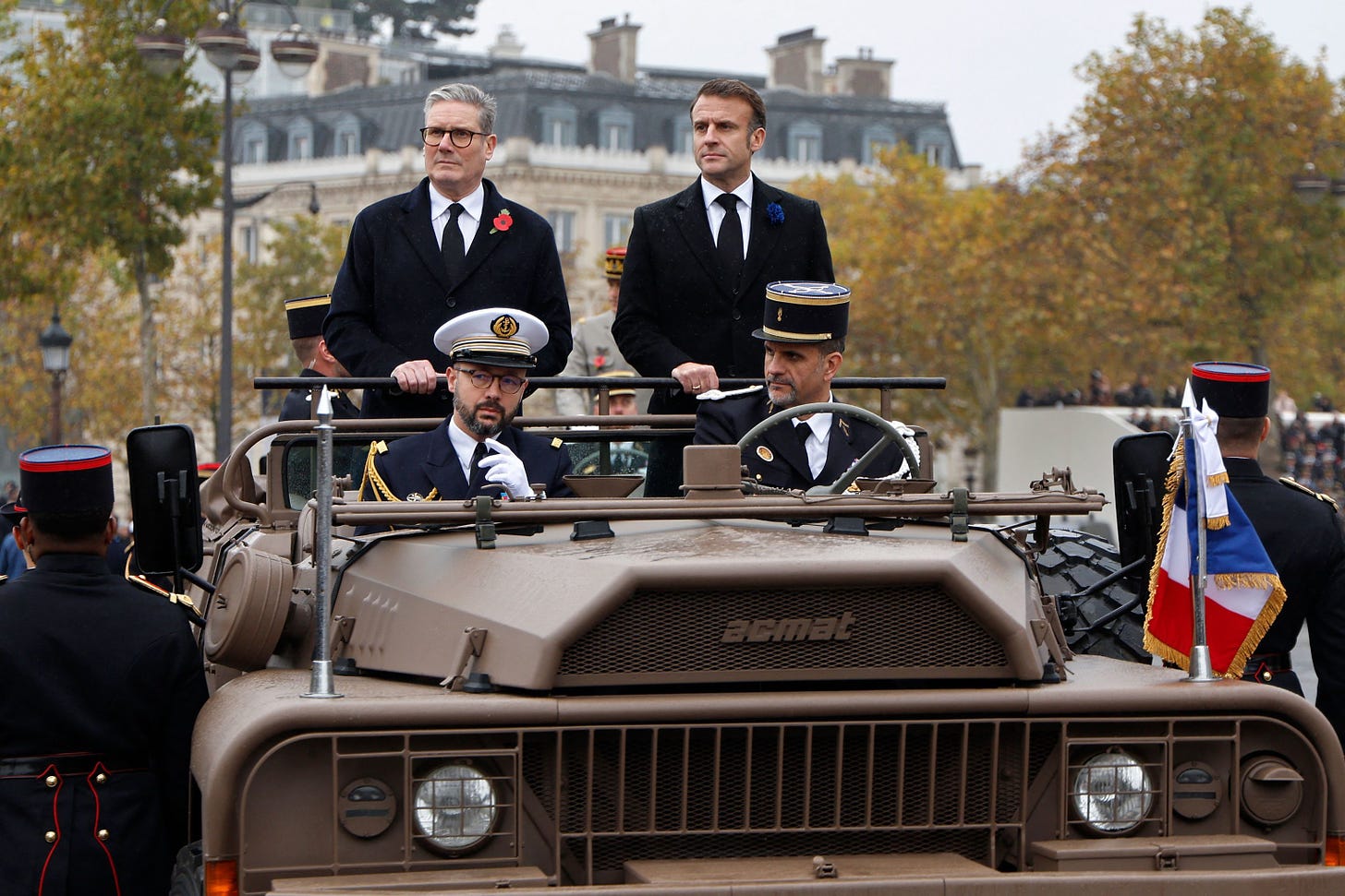 El presidente de Francia, Emmanuel Macron,  y el primer ministro de Gran Bretaña, Keir Starmer, pasan revista a las tropas a bordo de un vehículo de mando en la Place de l'Etoile.