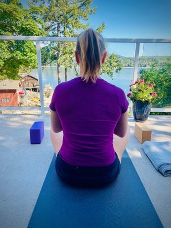 woman sitting on yoga mat in front of the ocean