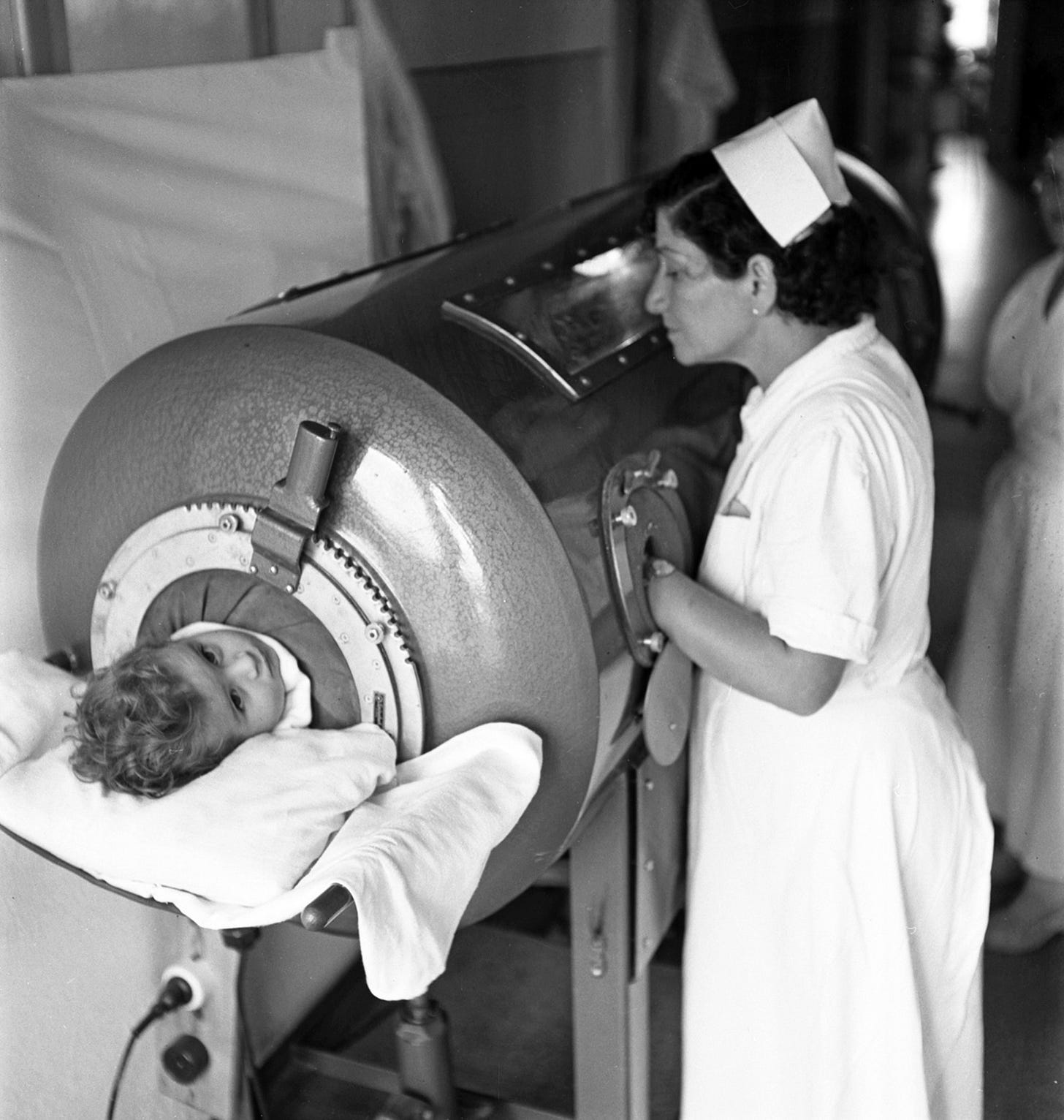 Nurse attending to child in an iron lung