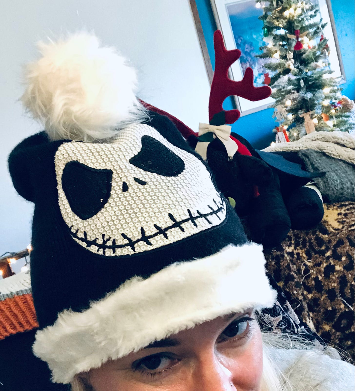 The author peeks up at you from beneath a black hat with white fuzzy trim and pompom and a sequined Jack Skellington