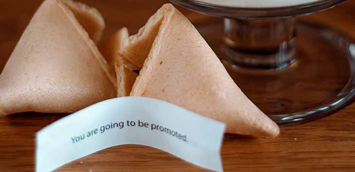 Photo of a fortune cookie broken open to reveal a slip of paper containing the message: "You are going to be promoted."