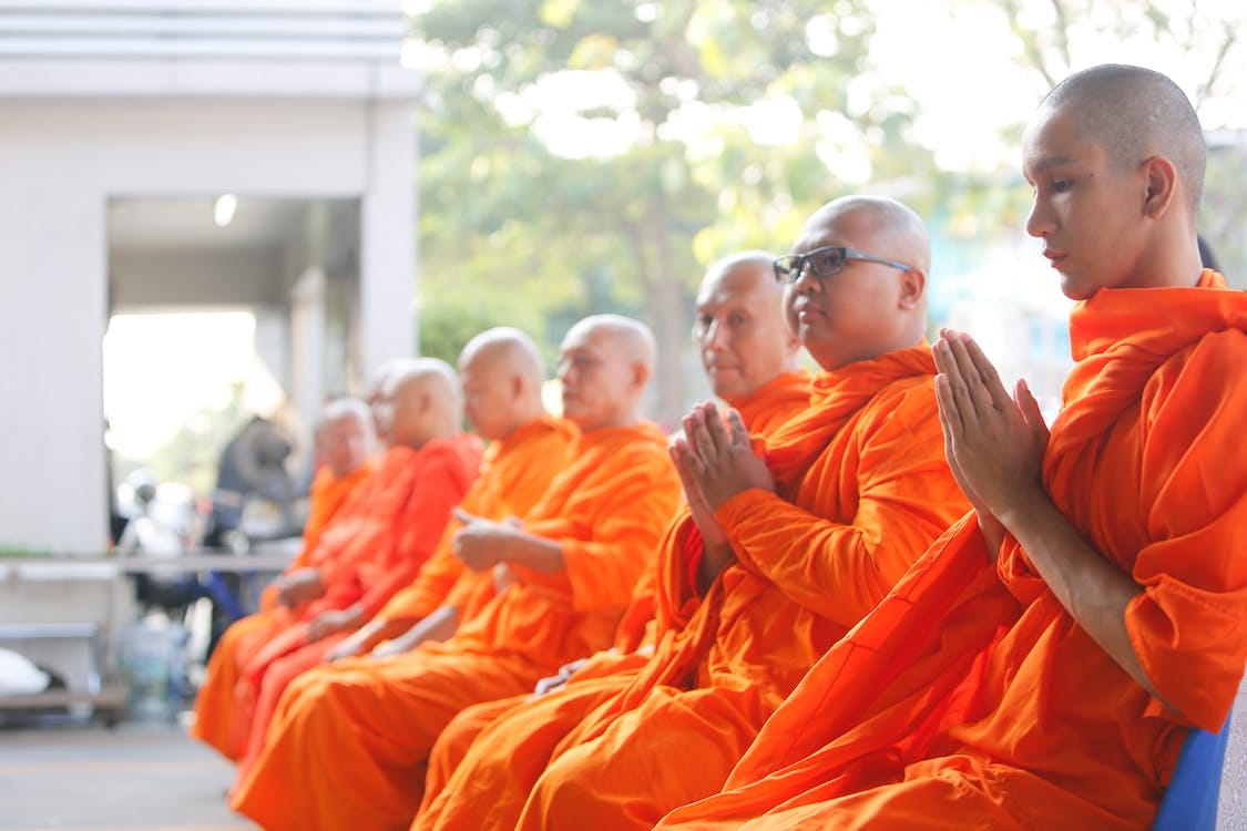 Free Group of Monks Sitting Near White Concrete Building Stock Photo
