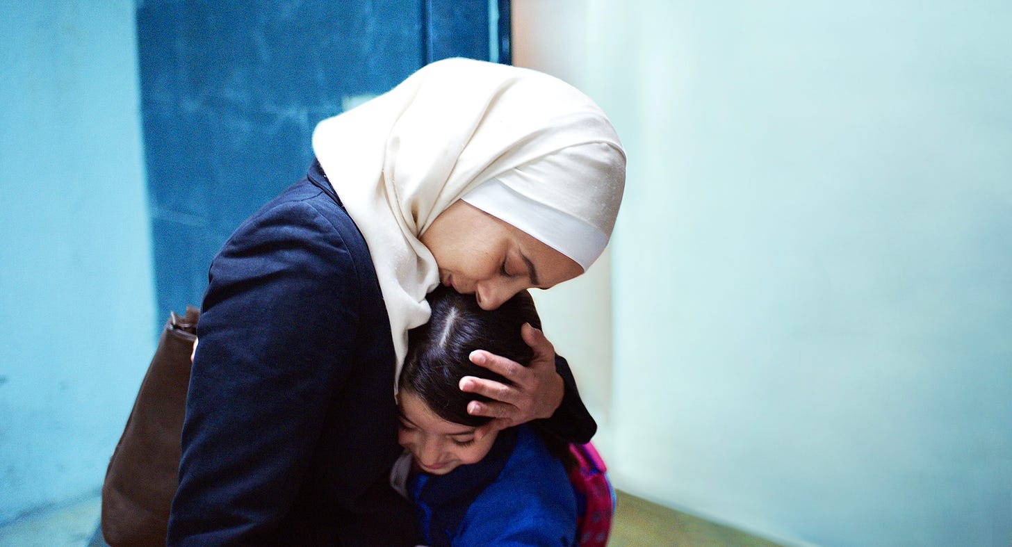 A Jordanian woman in a headscarf embraces her daughter