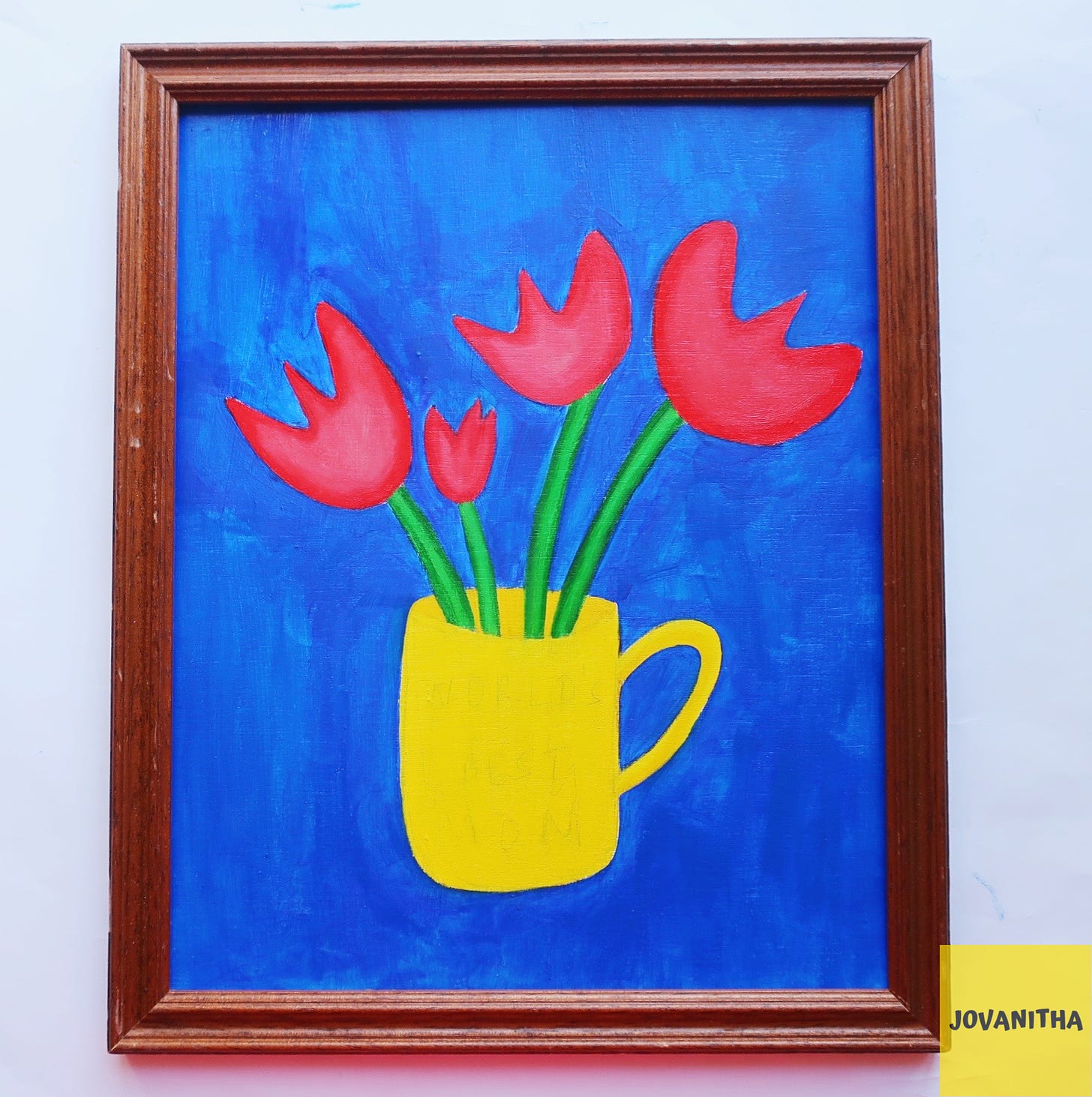 An oil painting of four red tulips in a yellow mug on a blue background in a thrifted frame