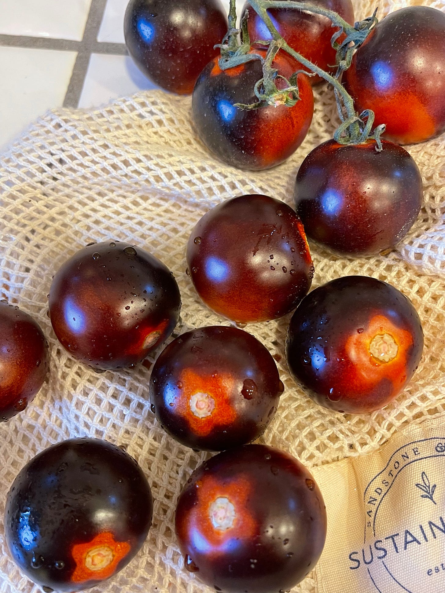 Small round tomatoes washed and sitting on a knit bag