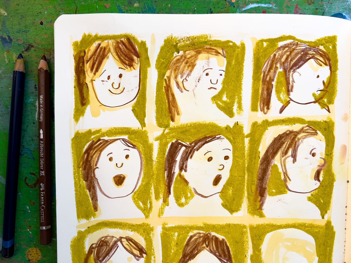 a grid of faces drawn in a sketchbook