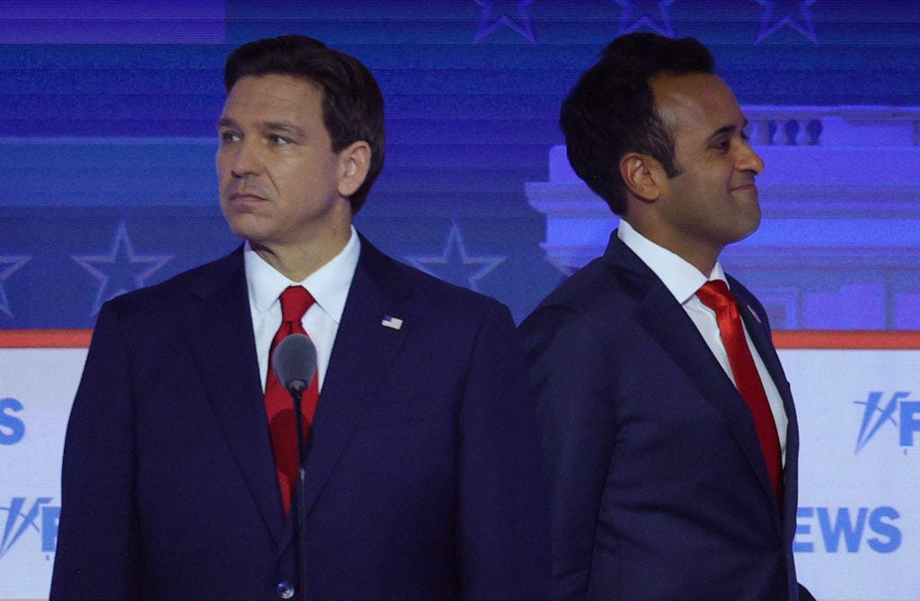Former biotech executive Vivek Ramaswamy passes behind Florida Governor Ron DeSantis during a break at the first Republica...