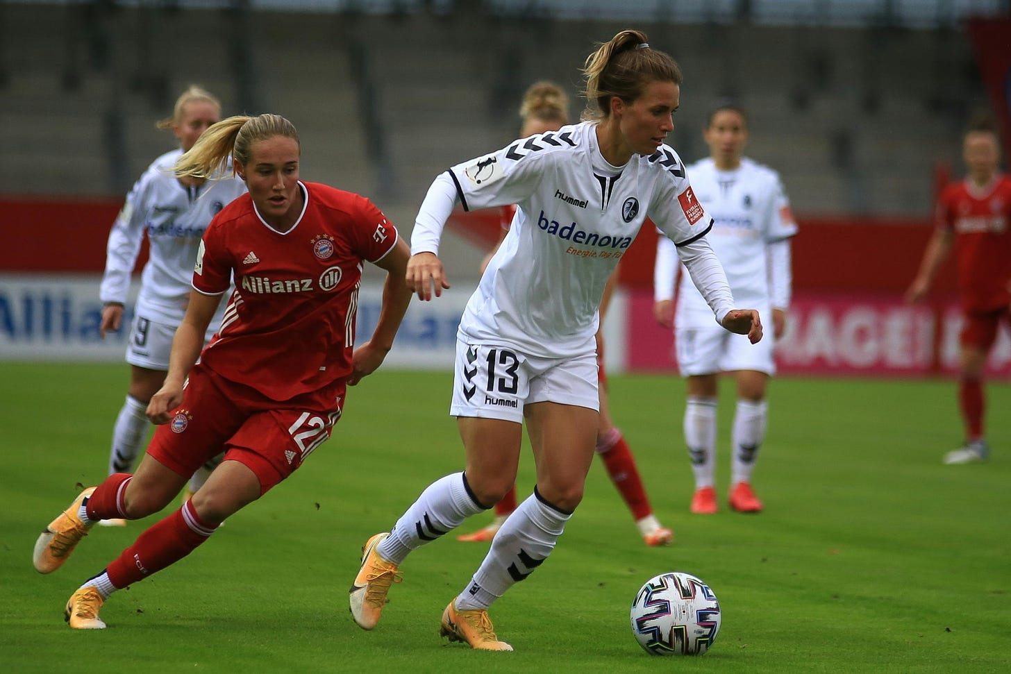 Women in red and white uniforms playing soccer