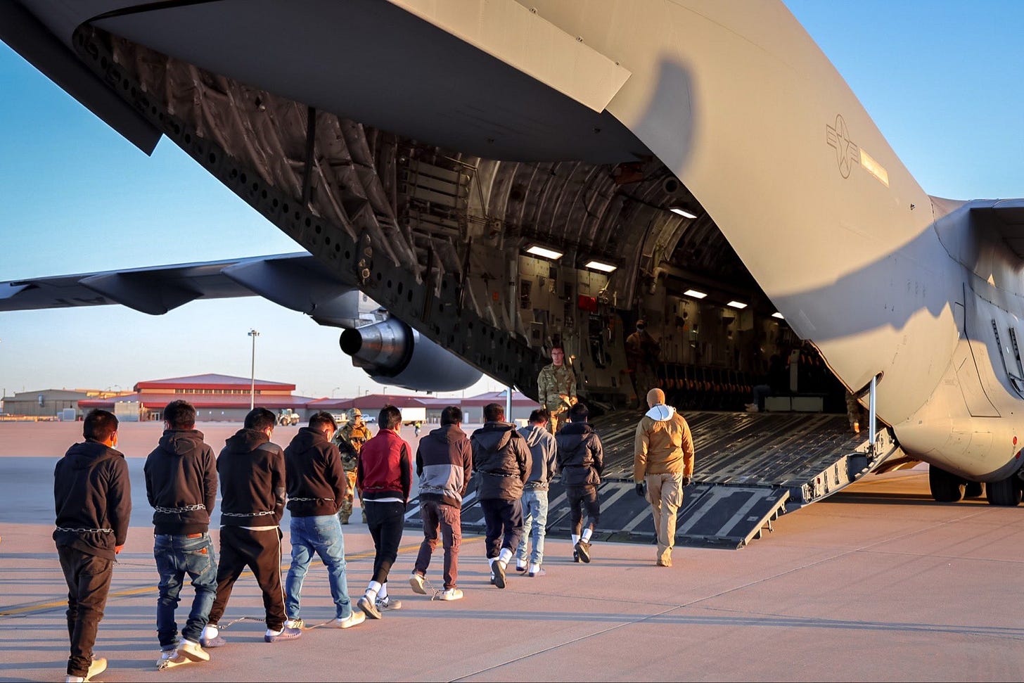Personas deportadas con grilletes en pies y manos, entrando a un avión militar. El espectáculo de las deportaciones satisface al electorado y provoca terror entre los migrantes. Foto: X/PressSec Personas deportadas con grilletes en pies y manos, entrando a un avión militar. El espectáculo de las deportaciones satisface al electorado y provoca terror entre los migrantes. Foto: X/PressSec