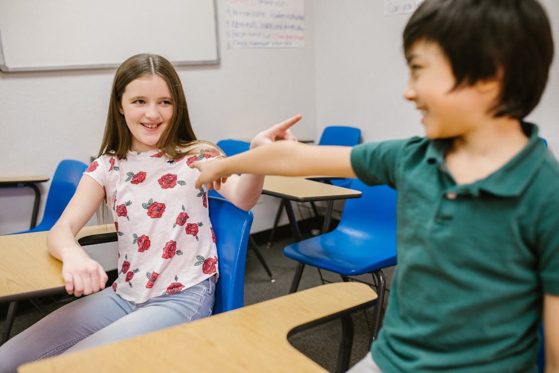 Free Two children playfully interacting in their classroom environment, showcasing positive energy. Stock Photo