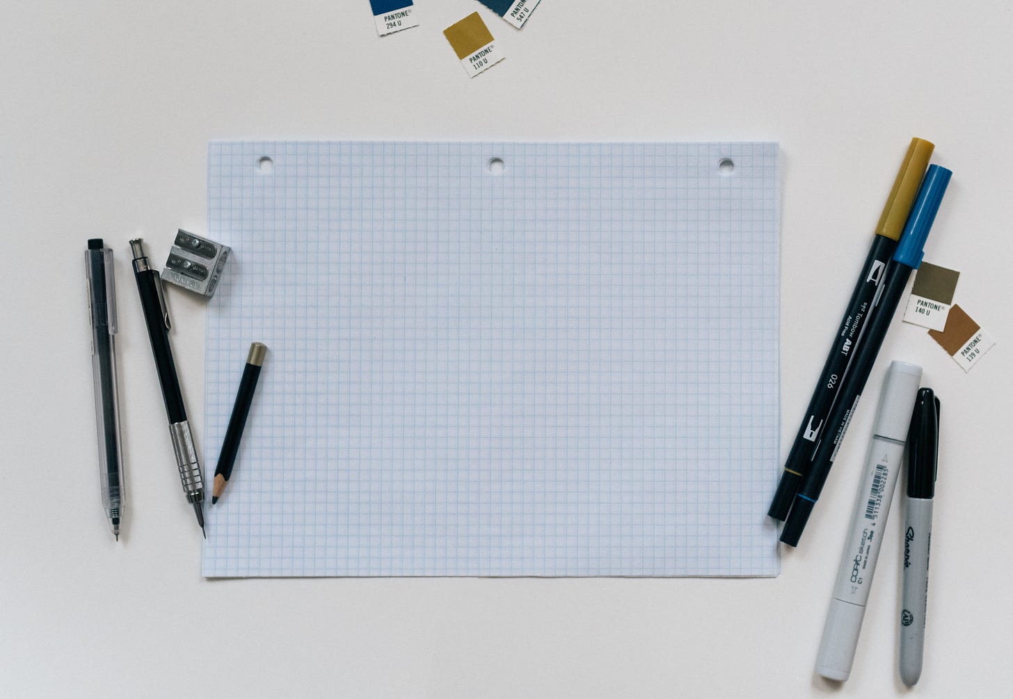 A blank piece of graph papers with pencils to the left and markers on the right