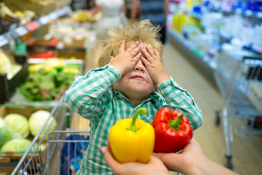 Boy in shopping cart with hands over his eyes, about to choose between a yellow pepper and a red pepper, gratitude, law of attraction, Tim’s Gratitude Experiment
