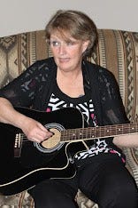 Kimmie sitting on a Davenport with a cheap Indiana guitar, singing her heart out.