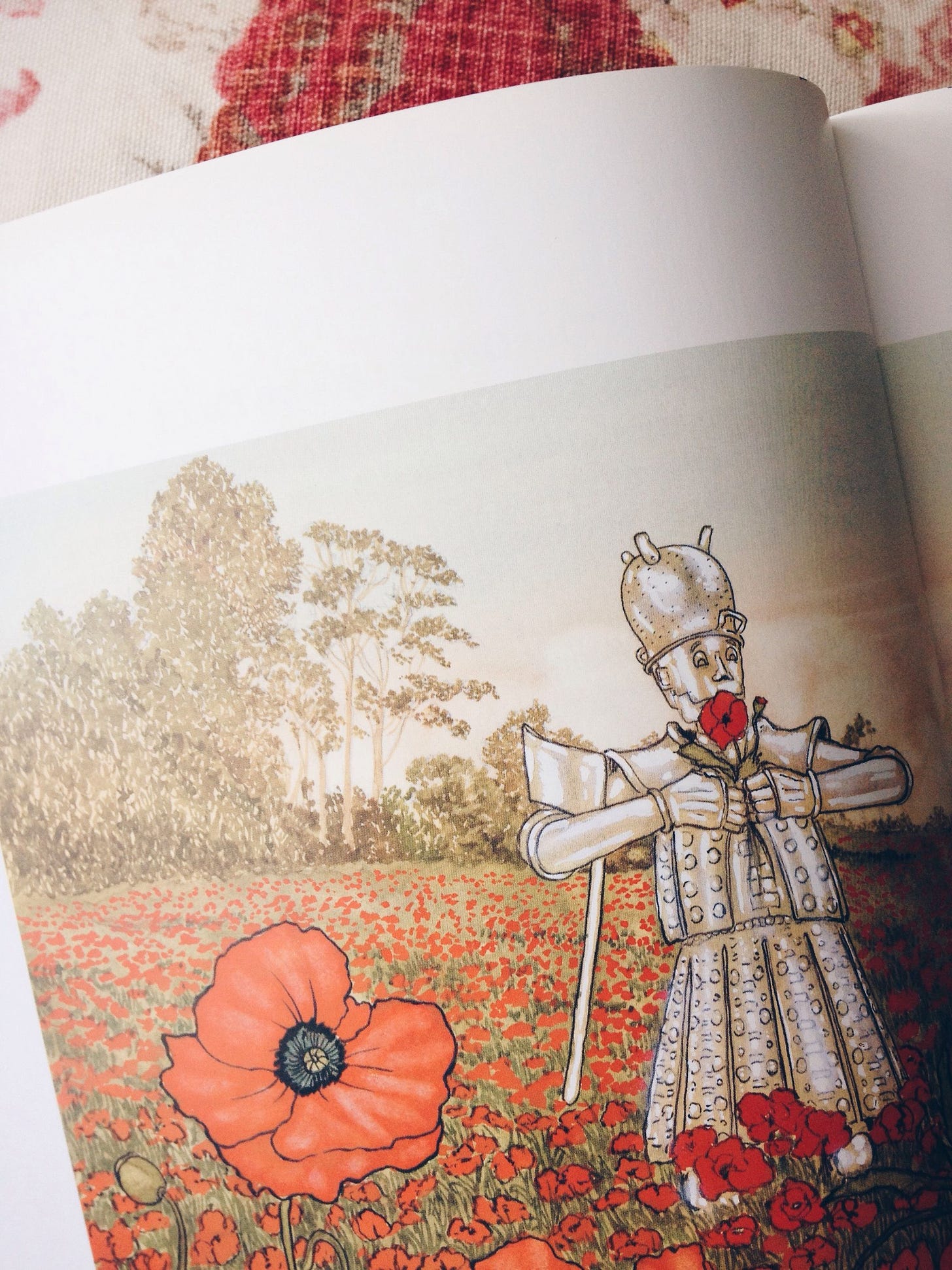Illustration of the Tin Man from The Wizard of Oz holding red poppies, standing in a field of poppies.