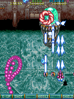 A screenshot showing the boss fight from stage 3 against a jellyfish-looking ship, which has fired off a shifting, squirming segment of attached purple orbs, which float around in an ever-shifting form you need to avoid.