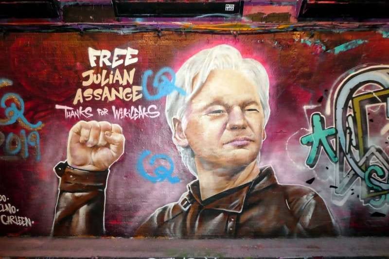 Graffiti mural of Julian Assange with his right arm raised, with the words "Free Julian Assange.  Thanks for Wikileaks."