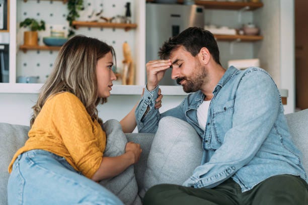 Worried couple talking together in the living room at home. Shot of young wife expressing empathy and compassion to her sad frustrated husband. Emotional communication stock pictures, royalty-free photos & images