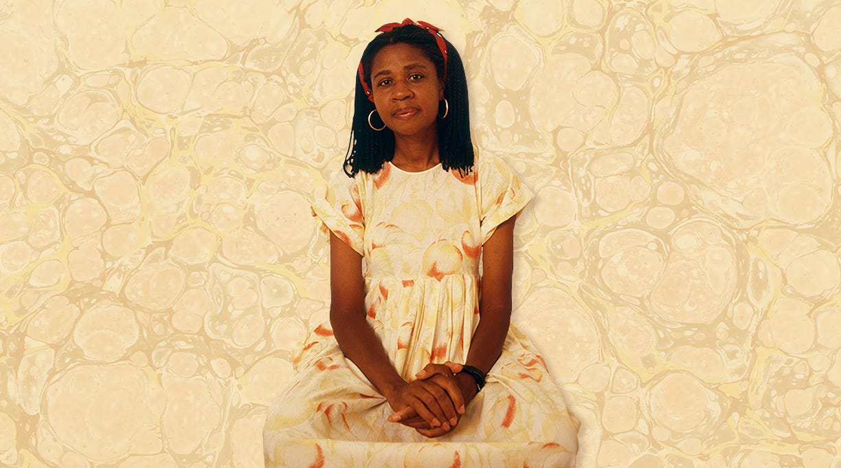 A younger Kincaid, a Black woman with loose shoulder length locs, orange headband, gold hoop earings, in a yellow and white circular patterened dress seated with her hands clasped between her legs, gaze straight at the camera. Weird, ugly yellow marble pattern in background courtest of Kirkus Reviews.