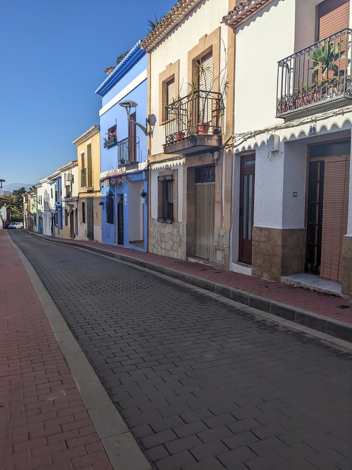 An empty European street with colorful houses with balconies.