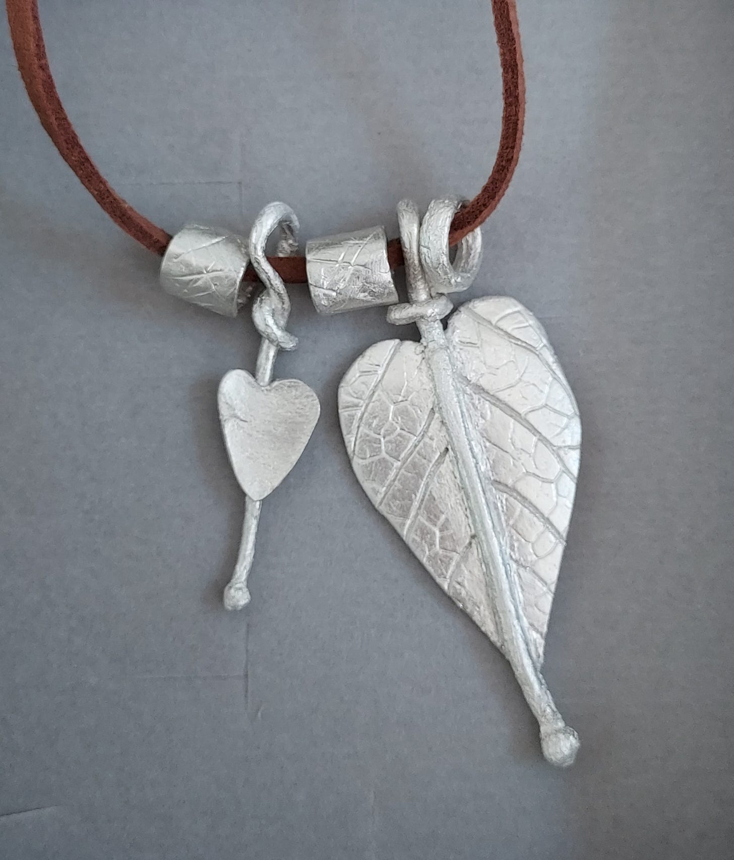 Silver leaf pendants on a brown leather cord