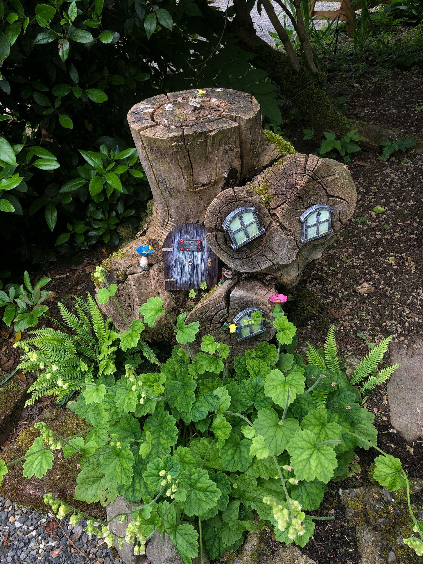 a stump with windows and a door on it made to look like a fairy house