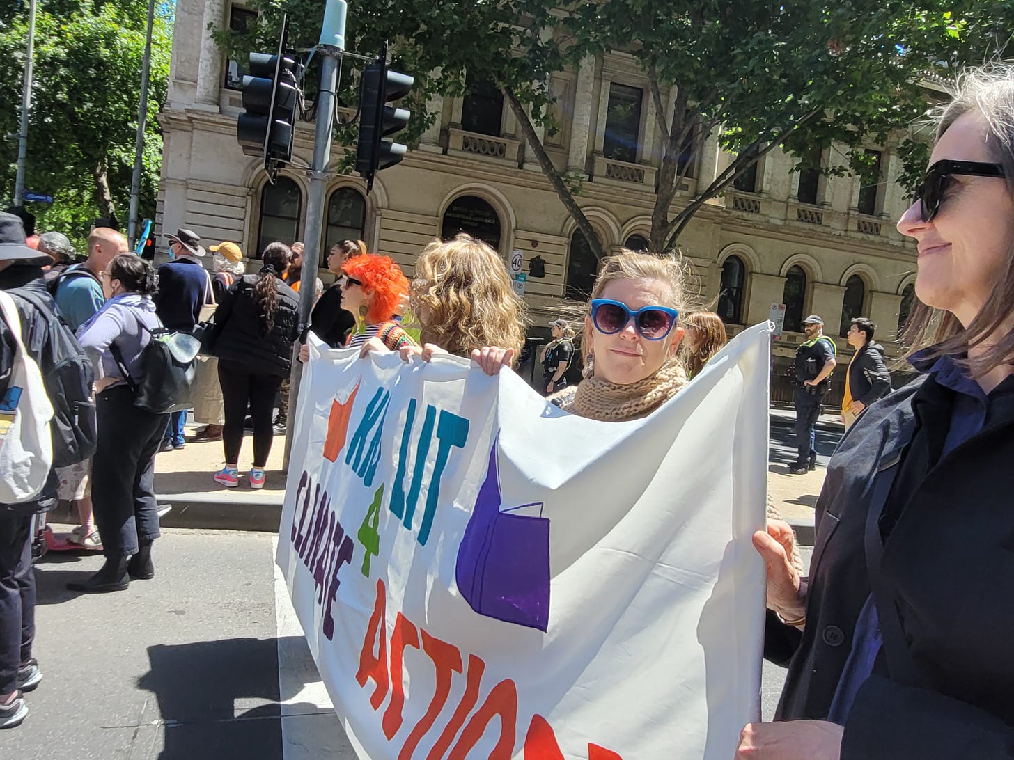 4 women holding a banner in a protest. Banner reads Kid Lit for Climate action.