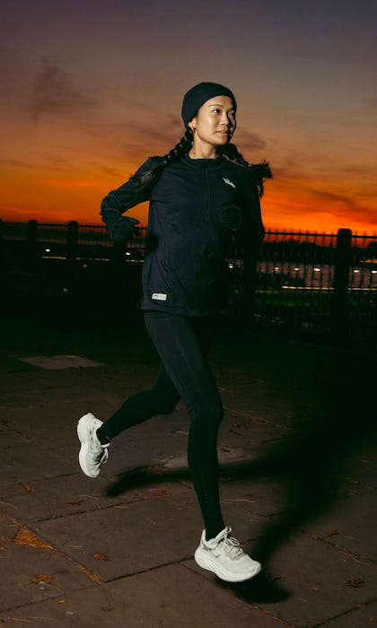 A runner, wearing an all-black Bakline outfit, runs as the sun sets in the background.