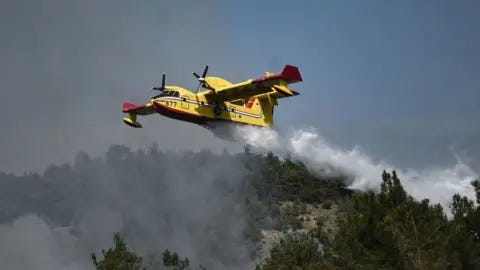 Getty Images A plane drops water over wildfires spreading in Dadia forest, one of the most important areas in Europe for birds of prey