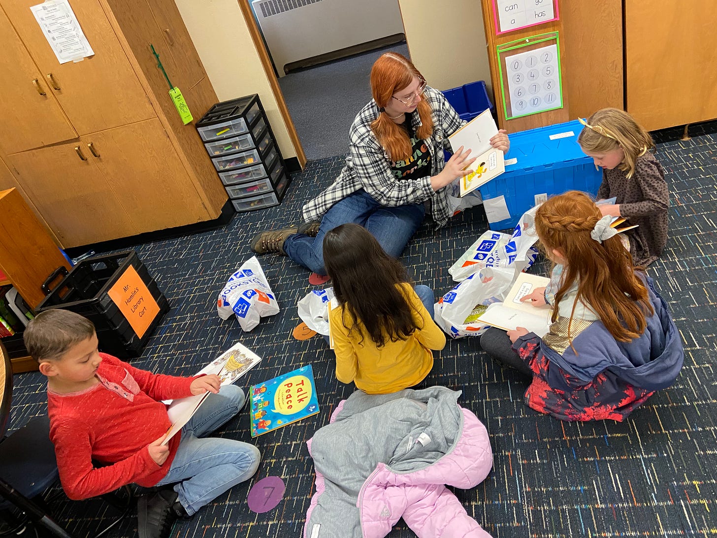 Young woman reads to a group of first-graders, who follow along in books of their own