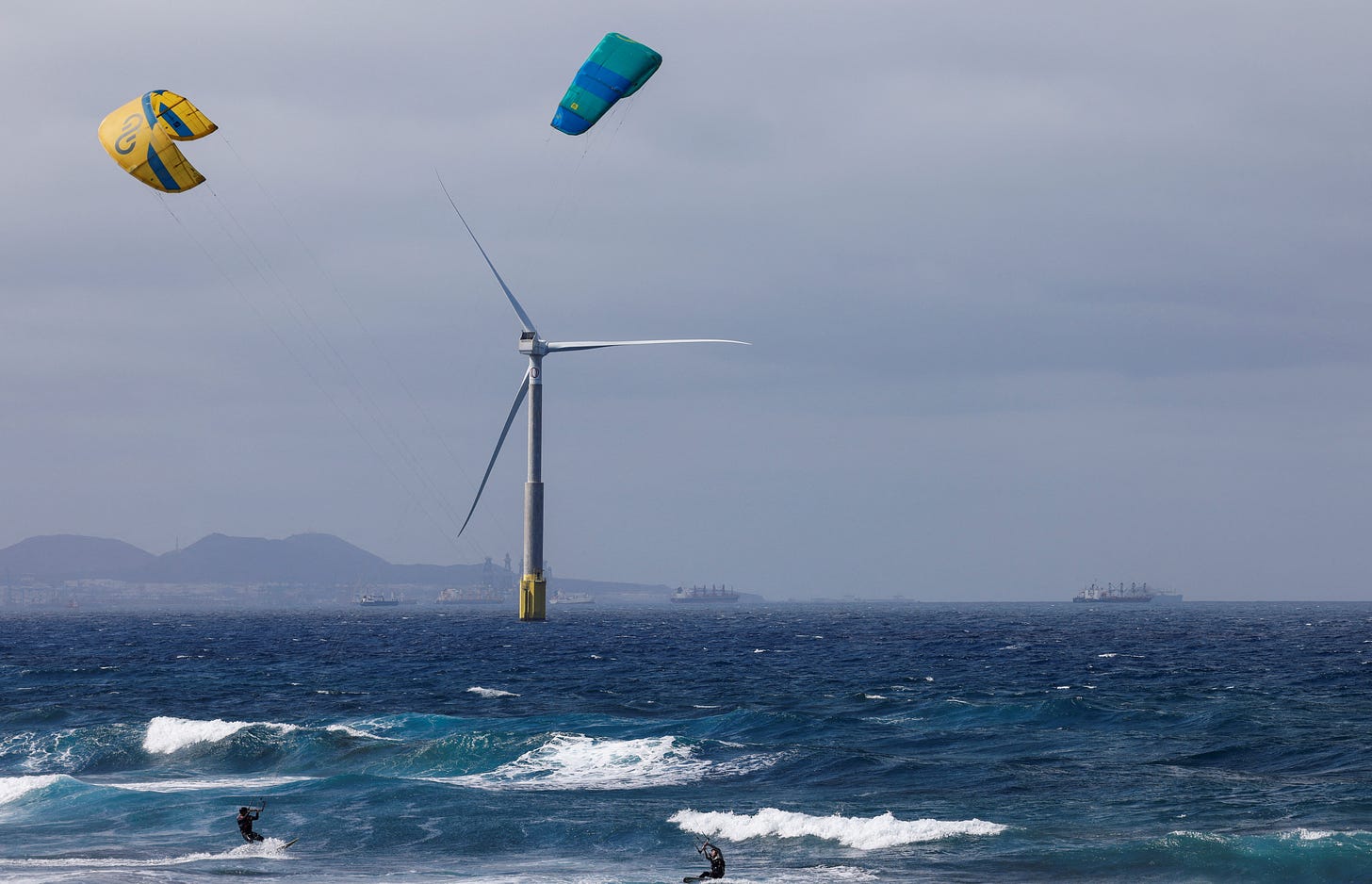 Two sportsmen sail near an offshore wind turbine of the Siemens Gamesa company is seen from the Telde coast on the island of Gran Canaria
