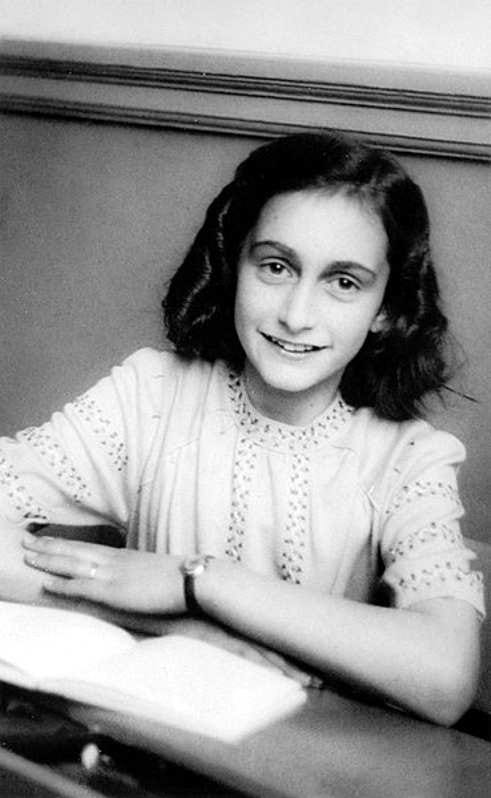 Anne Frank sitting at a desk with a book open in December 1941.